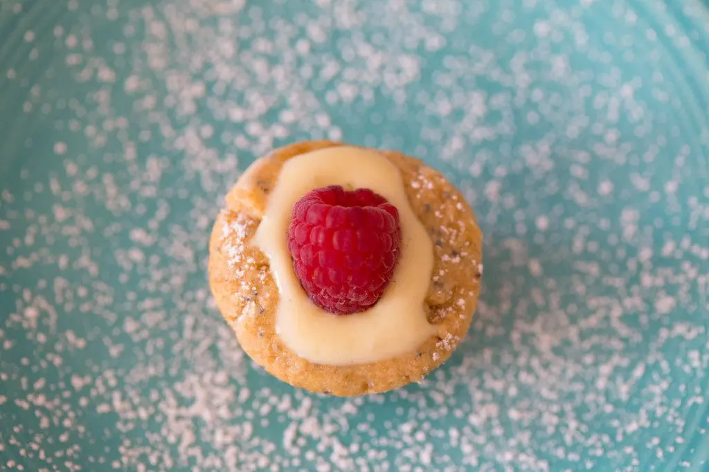Lemon blossom shortbread cookies on a turquoise plate with a fresh raspberry