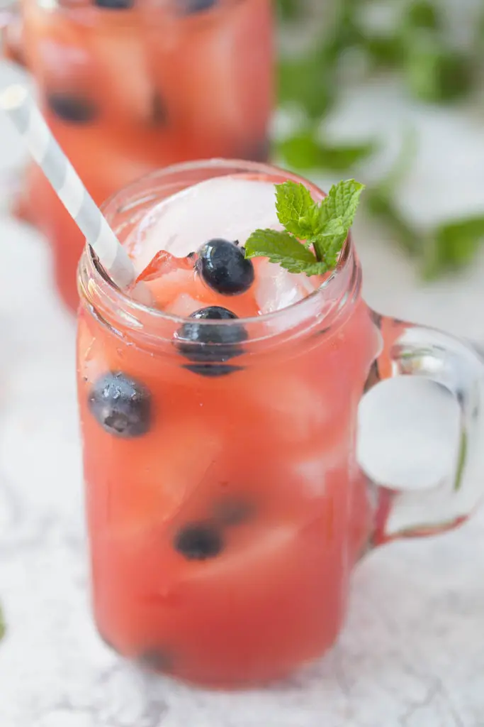 Close up of watermelon rum runner cocktails with blueberries and a sprig of fresh mint