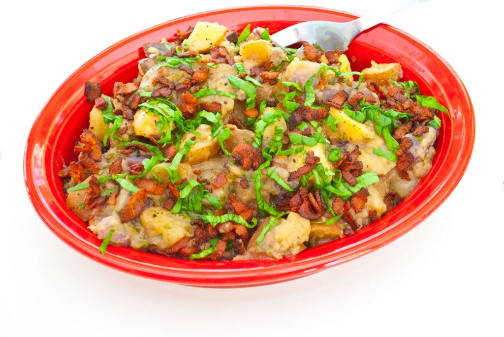 Red, White, and Blue Potato Salad in red bowl covered with chopped fresh basil