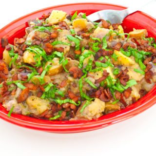 Red, White, and Blue Potato Salad in red bowl covered with chopped fresh basil