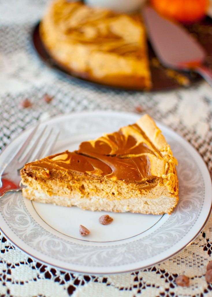 Easy pumpkin cheesecake with a cinnamon chip swirl on a white plate over a lace tablecloth