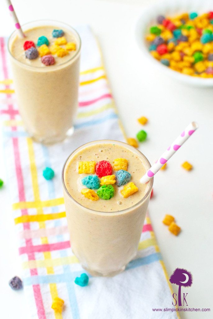Two crunch berry banana smoothies on a white cloth with pastel stripes and crunch berry cereal sprinkled about