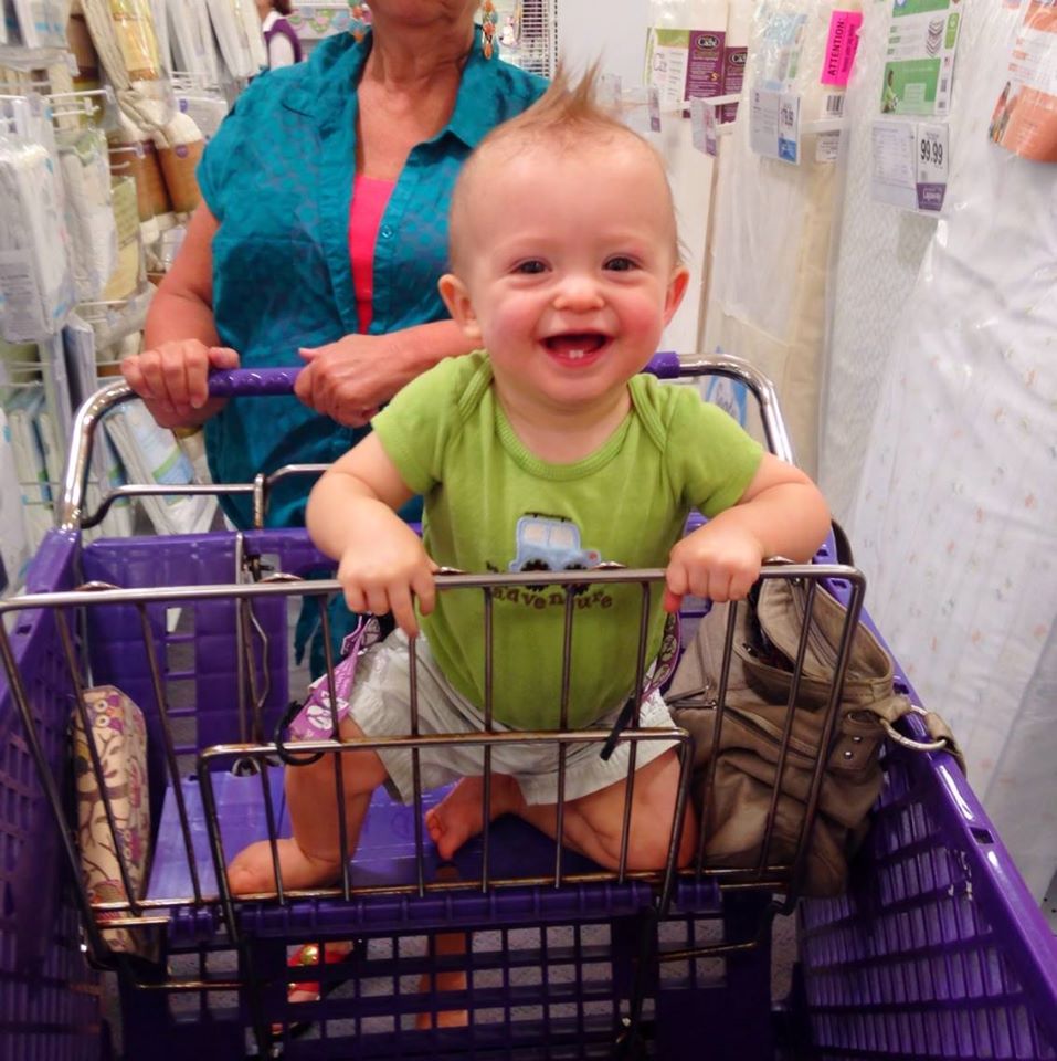 Baby boy in a purple buggy with a green shirt and a huge smile