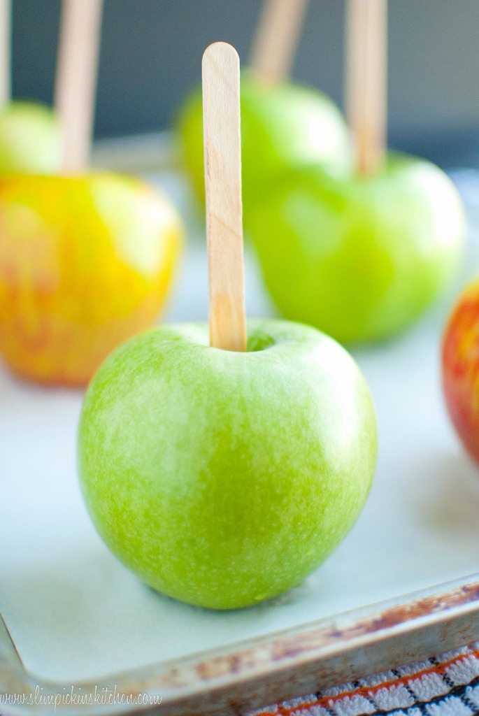 Green apple with a popsicle stick standing up on a baking sheet
