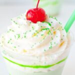 Close up of no bake shamrock shake no bake cheesecake with whipped cream and cherry on top