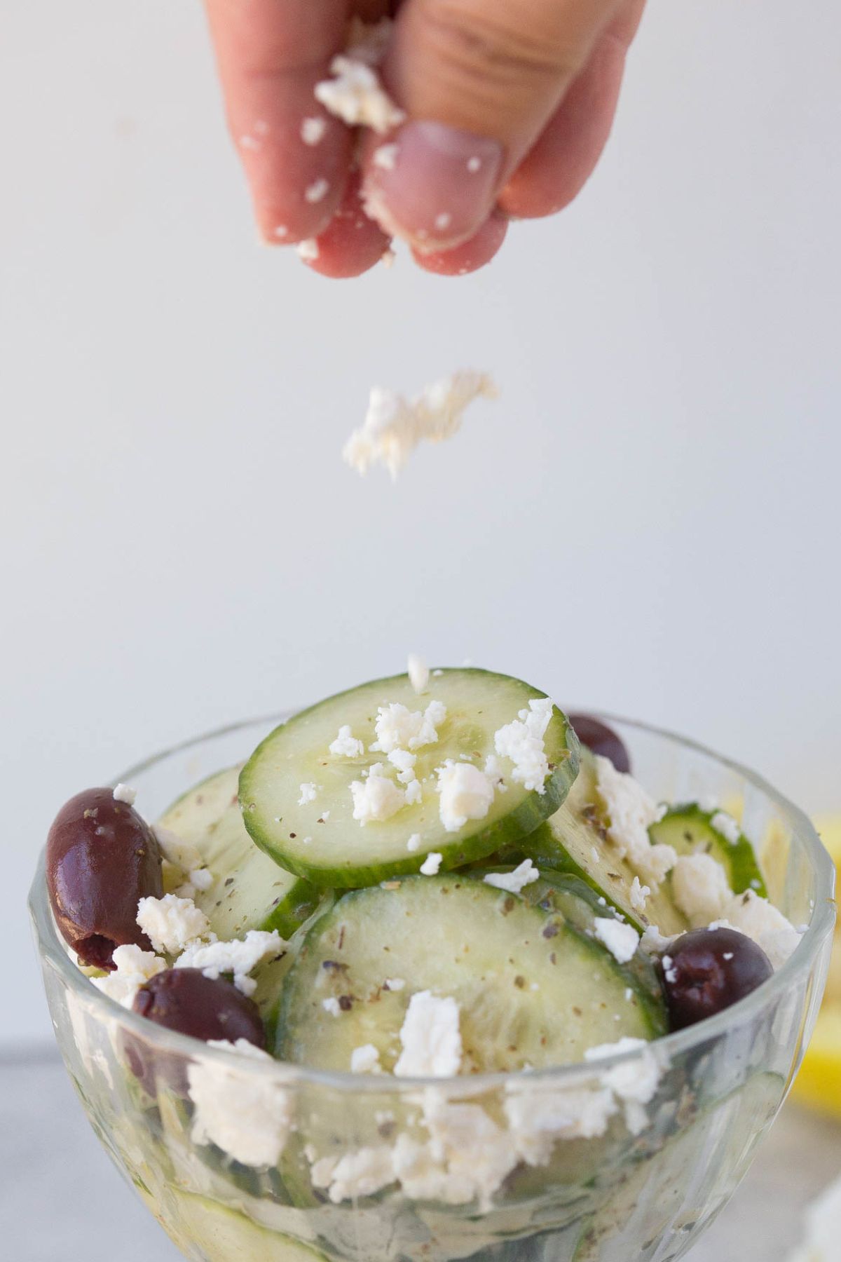 feta cheese being sprinkled onto cucumber salad
