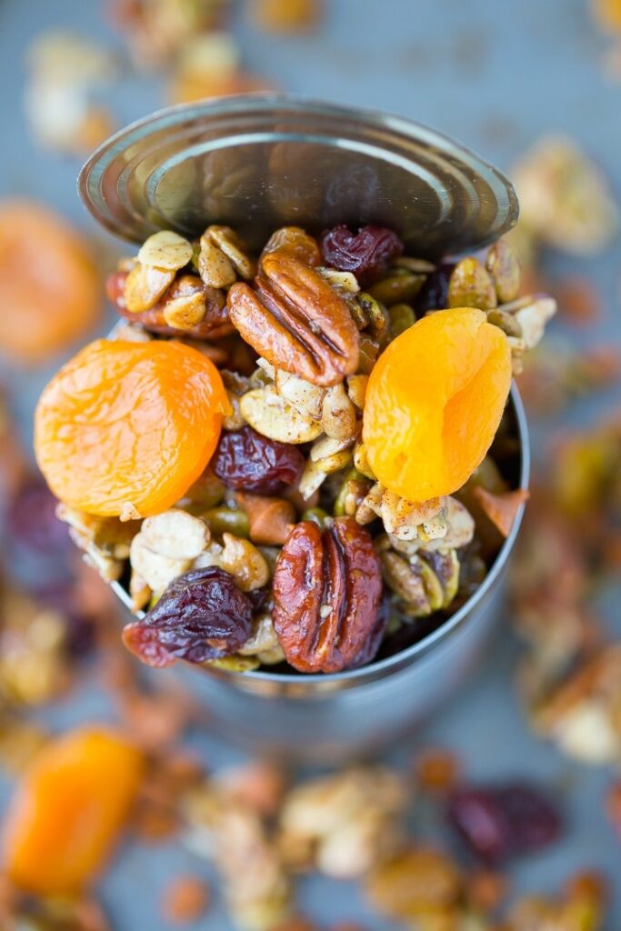 close up photo of maple pumpkin spice trail mix in a tin can  with pecans, apricots, and pumpkin seeds