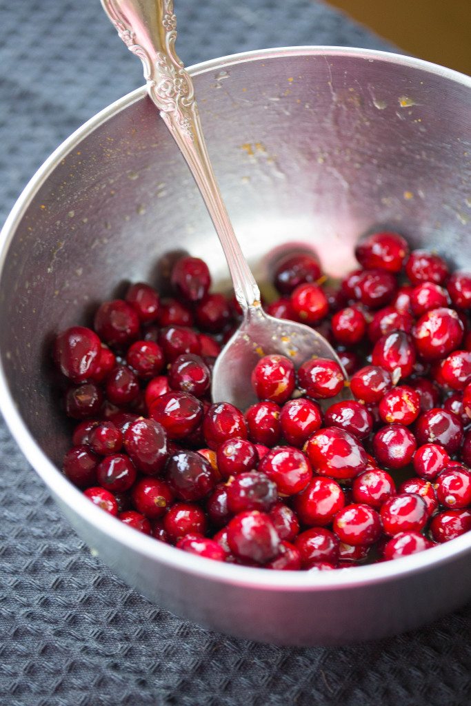 Whole fresh cranberries in a silver bowl with a silver spoon