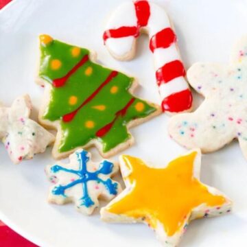 The best Christmas cut outs decorated with colored icing on a white plate.