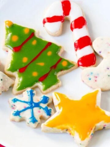 The best Christmas cut outs decorated with colored icing on a white plate.
