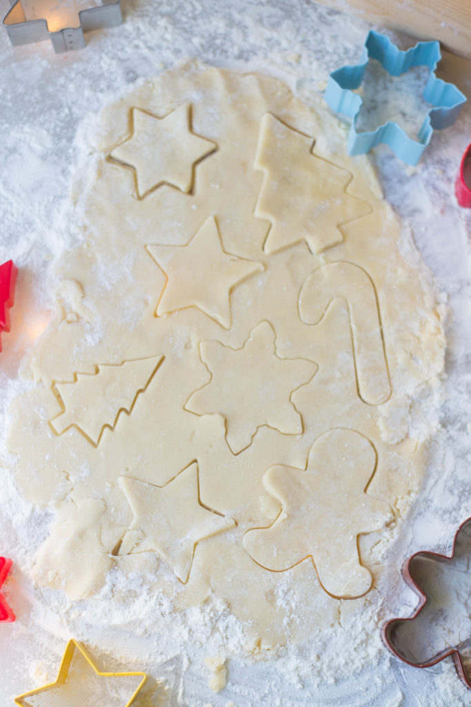 Christmas sugar cookie dough on floured surface with cookie shapes cut out in dough