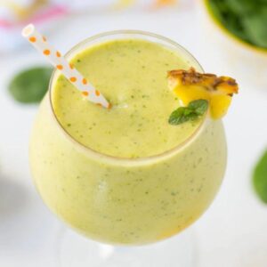 tropical green smoothie in a big globe glass garnished with pineapple