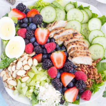 Green Cobb Salad With slivered almonds, a hard boiled egg, mixed berries, grilled chicken, sliced cucumber, and chopped bacon