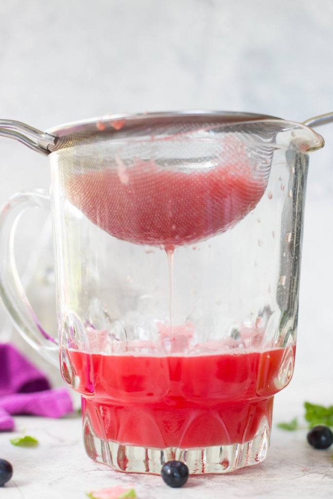 Watermelon juice straining into glass pitcher