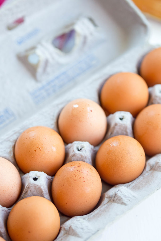 a dozen brown eggs in a carton