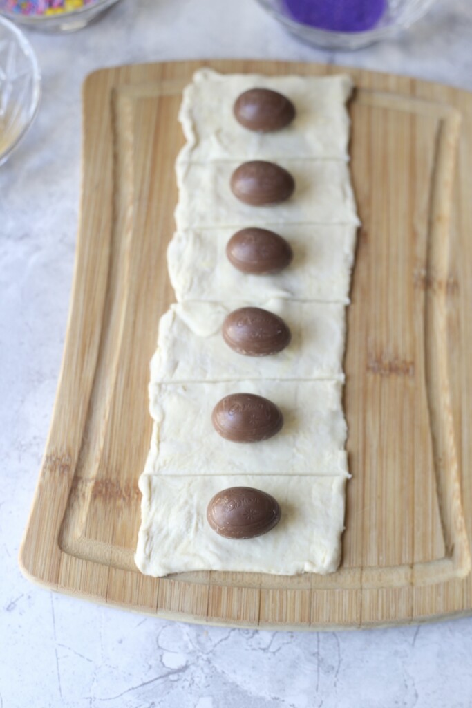 Mini Cadbury creme eggs lined up on puff pastry sheets to make easy chocolate croissants