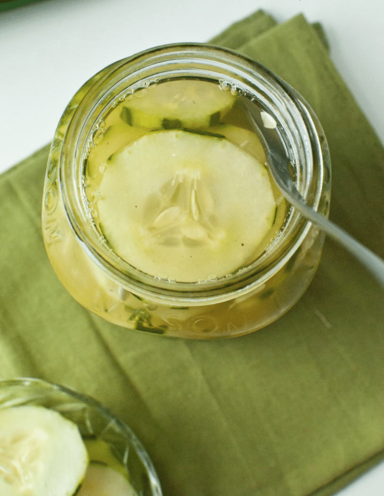 overhead shot of cucumbers and vinegar in a mason jar