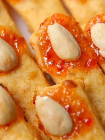 witch fingers cheese straws with red pepper jelly and marcona almonds on a white plate