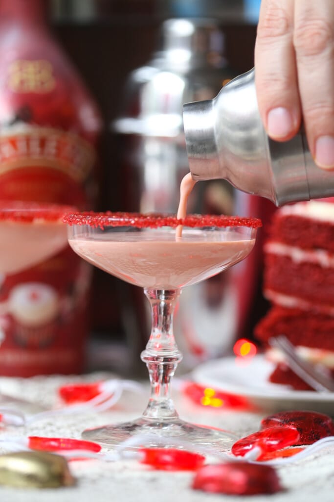 Red velvet chocolate martini being strained into a red sugar rimmed galss