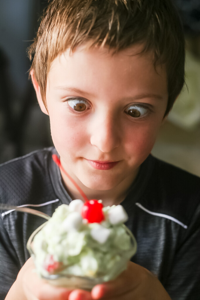 Watergate Salad in a glass sundae jar being ogled by a little boy with big hazel eyes