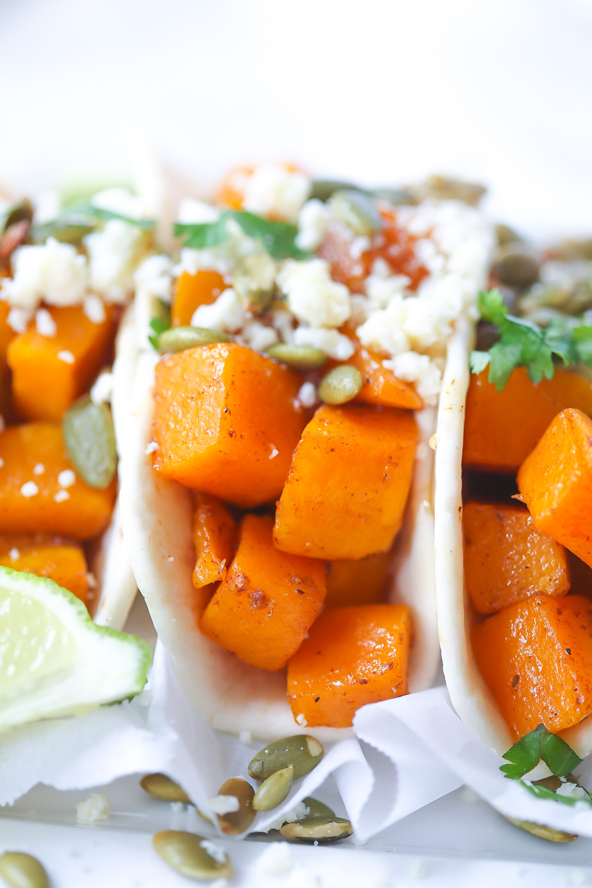 close up of diced roasted butternut squash tacos topped with crumbled white cheese