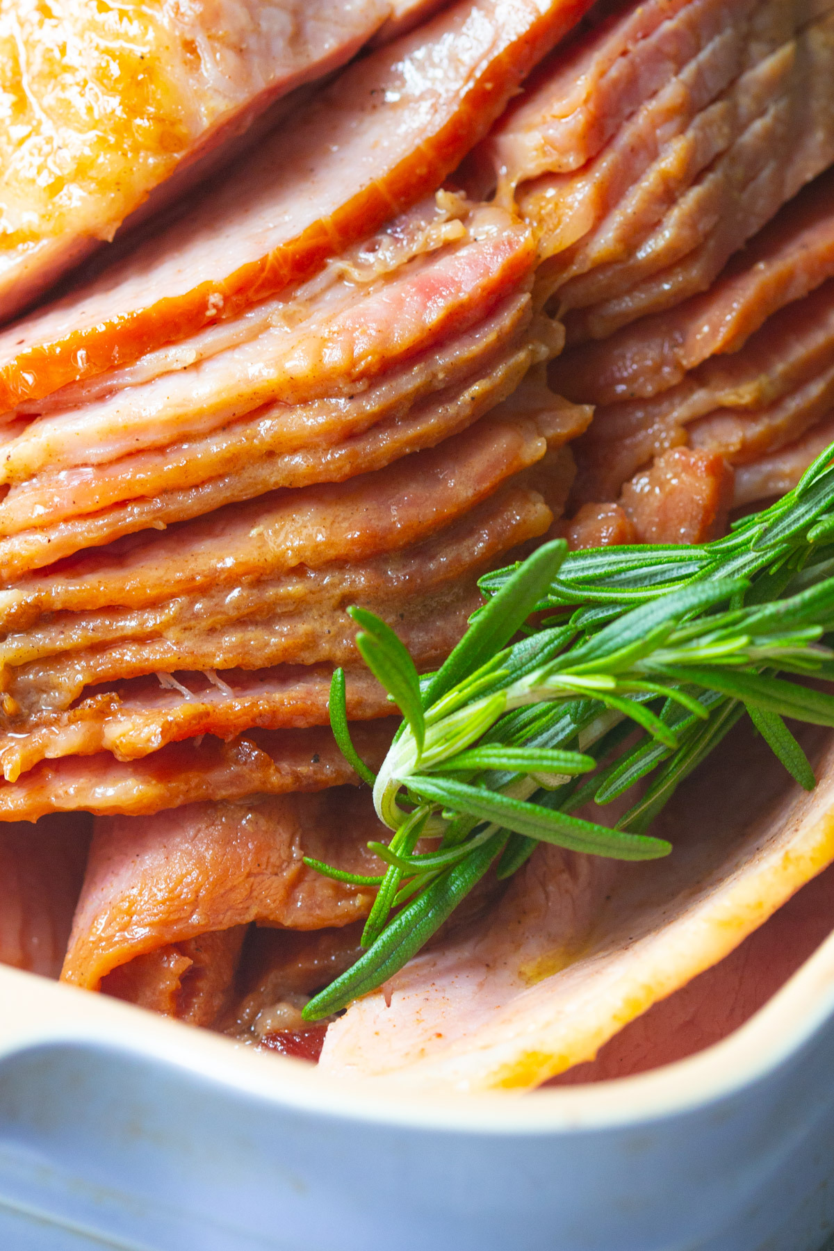 Slices of spiral ham (honey glazed ham) garnished with a sprig of rosemary