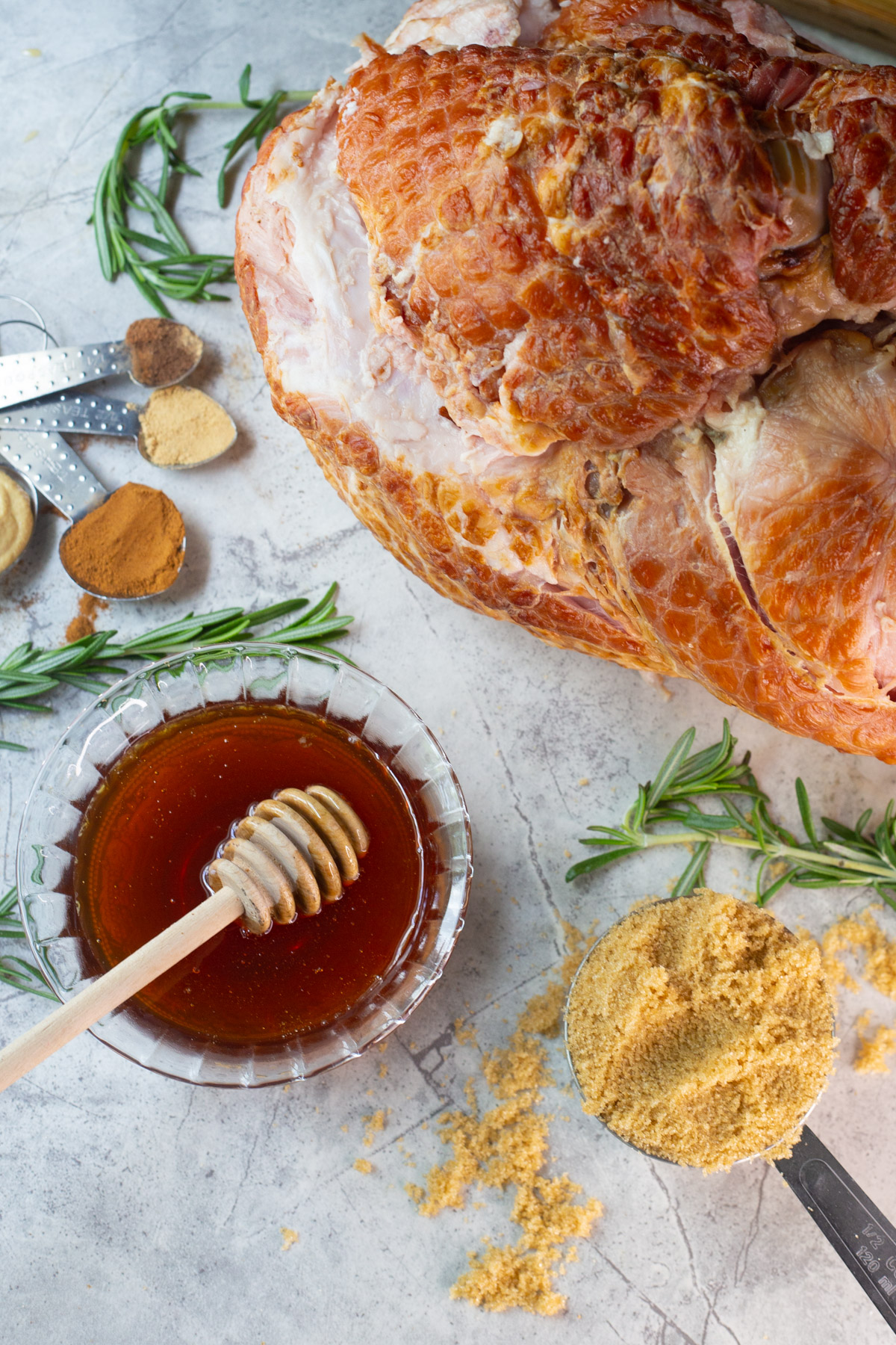Ingredients for a honey glazed ham: spiral ham, warm honey, brown sugar, cinnamon, and spices. 